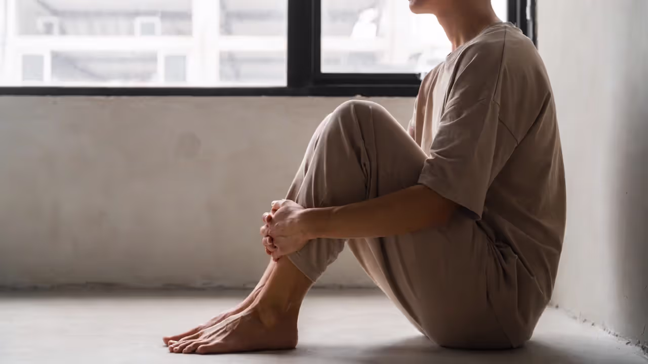 Adult sitting calmly by a window, symbolizing self-compassion and inner child healing.